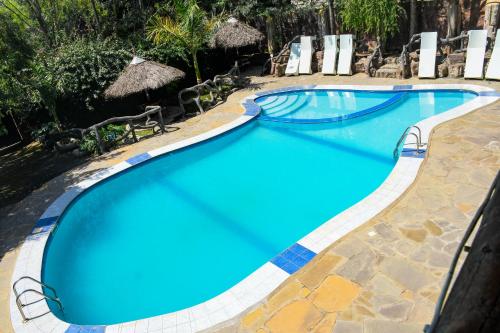 a swimming pool at a resort with chairs and umbrellas at Dovenest Lodge in Naivasha