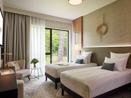 a hotel room with two beds and a window at Domaine du Liziec Vannes - MGallery Collection in Vannes