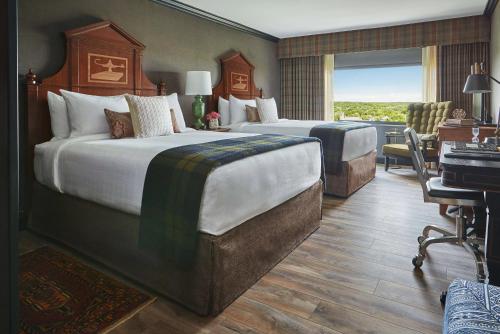 a hotel room with two beds and a desk at Graduate by Hilton Ann Arbor in Ann Arbor
