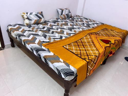 a bed with a comforter on it in a room at Aniruddha Home Stay in Ujjain