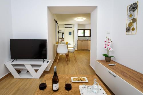 a living room with a television and a table with wine glasses at Nicolas Urban Comfort Living in Souda