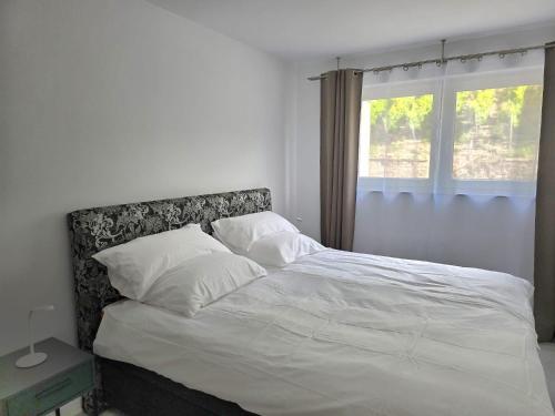 a bedroom with a bed with white sheets and a window at Ferienwohnungen Miller in Saarburg