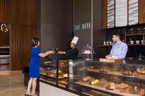 a woman is standing at a counter in a bakery at The Den, Bengaluru in Bengaluru