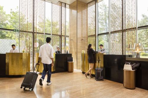 a group of people standing in a lobby with luggage at The Den, Bengaluru in Bengaluru