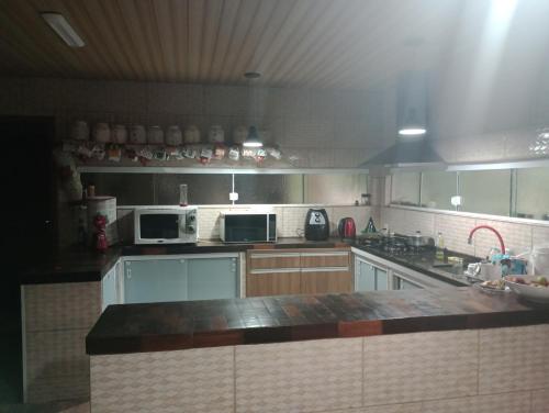 a large kitchen with a counter top and appliances at Casa Maria Rosa Quarto 1 in Blumenau