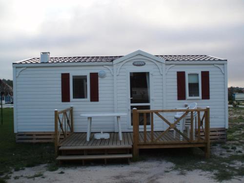 a small white house with a wooden deck at Bungalows Land'shause in Pataias