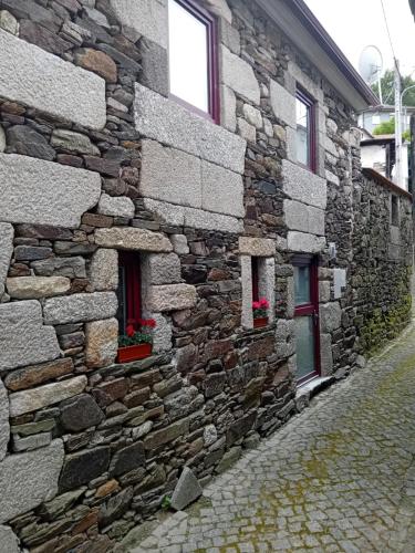 a stone building with two windows on a street at Casa do Alambique in Castro Daire