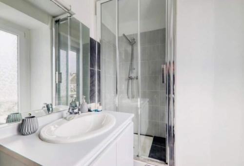 une salle de bain blanche avec un lavabo et une douche dans l'établissement Charmant studio proche Disneyland face à la gare, à Thorigny-sur-Marne