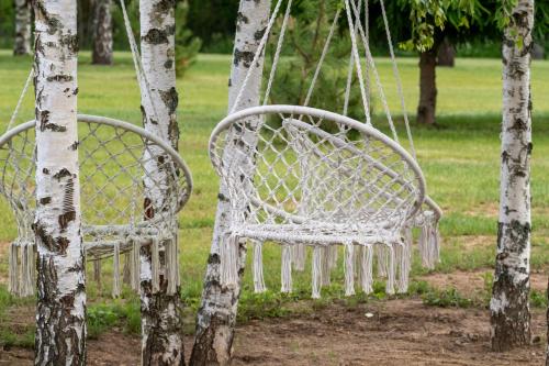two white chairs sitting next to a tree at Poilsio Vingis in Liūnai
