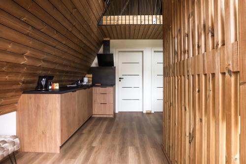 a kitchen with wooden walls and a wooden floor at Poilsio Vingis in Liūnai