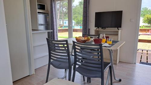 a dining room with a table and chairs and a television at Bungalows Land'shause in Pataias