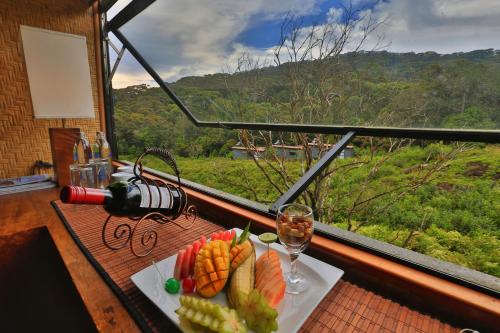 a table with a plate of food and a glass of wine at The Rainforest Ecolodge - Sinharaja with Shuttle Service from Car Park in Deniyaya