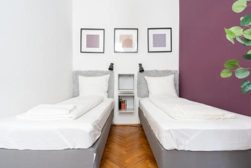 - 2 lits dans une chambre aux murs blancs et violets dans l'établissement Vienna City Apartments 1110 Vienna, à Vienne