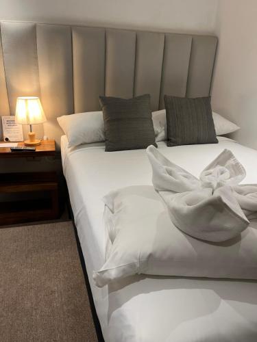 a bedroom with two beds with white sheets and a lamp at Grupo Hotelero Colibri in Panajachel