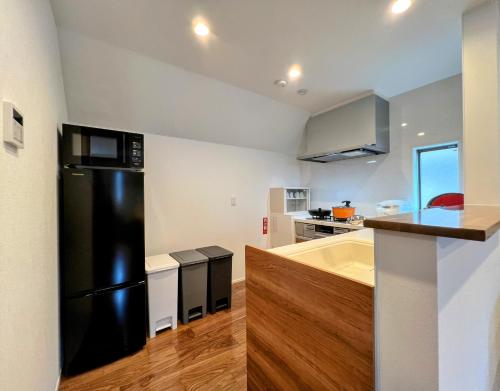 a kitchen with a black refrigerator and a sink at Brand New Modern Haven 7-Min Walk to Shinkoenji Station 9-Min Train to Shinjuku in Tokyo