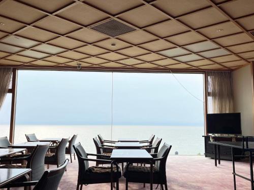 a dining room with tables and chairs and a view of the ocean at 瀬波 清波温泉 in Senami