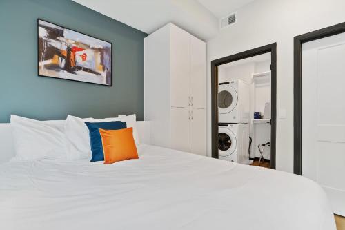 a bedroom with a white bed with an orange pillow at CozySuites on Mass with garage parking #14 in Indianapolis