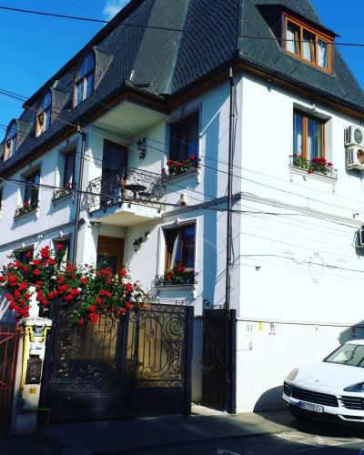 a white house with red flowers on the gate at Bucharest Boutique Accommodation by Hotels in Bucharest