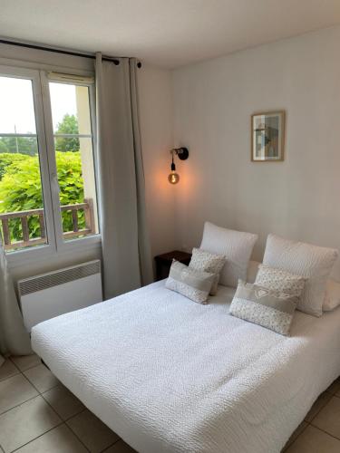 een slaapkamer met een wit bed met kussens en een raam bij Vue Sur Green in Levernois