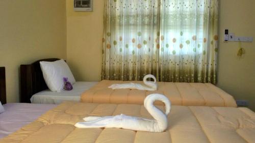 two swans sitting on two beds in a room at Lampang Lanna Home in Lampang