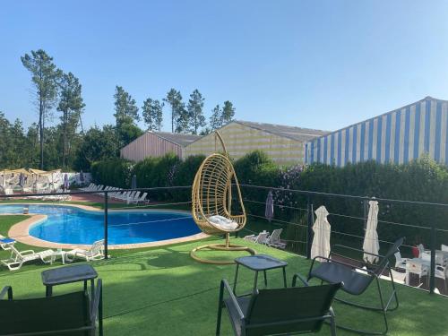 a patio with chairs and a wicker chair next to a pool at Hotel Rubi in Viseu