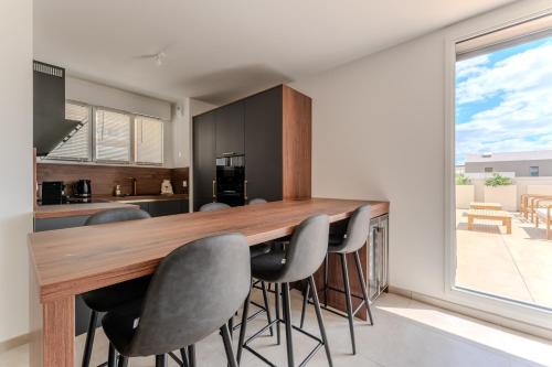 une cuisine avec un bar en bois et 4 chaises dans l'établissement Port Marianne à Montpellier avec terrasse XXL, à Montpellier