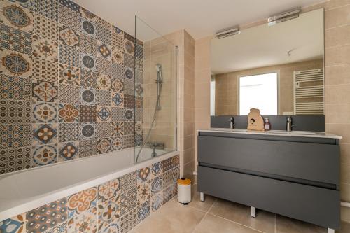 une salle de bain avec une baignoire, un lavabo et un miroir dans l'établissement Port Marianne à Montpellier avec terrasse XXL, à Montpellier