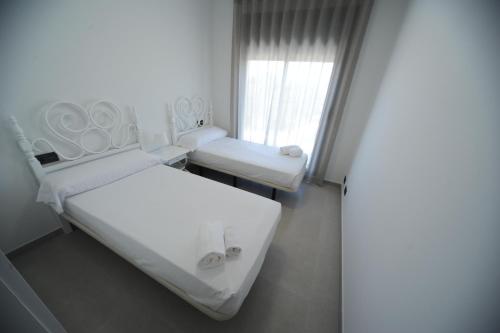 a white room with two beds and a window at ATICO BOHIO premium in Benicàssim