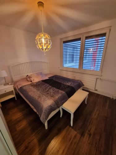 a bedroom with a large bed and a chandelier at Slnečný apartmán u Klaudii in Levice