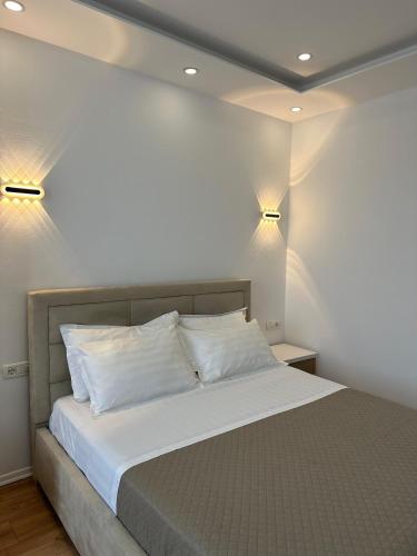 a bedroom with a bed with two lights on the wall at Hotel Arberia in Tirana