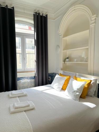 a large white bed with yellow pillows and a window at Large apartment on Rua Augusta in Lisbon