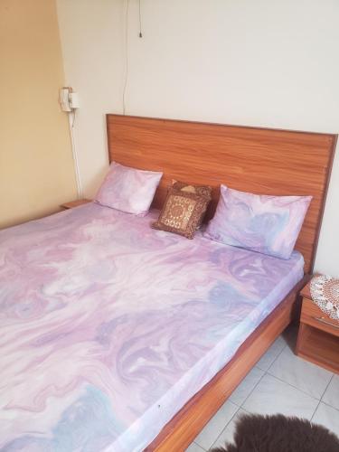 a bed with a wooden headboard and pillows on it at Chez Nafy in Saint-Louis