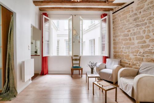 un salon avec un canapé et un mur de briques dans l'établissement GuestReady - Charmant Apt pour 2 au Cœur de Paris, à Paris