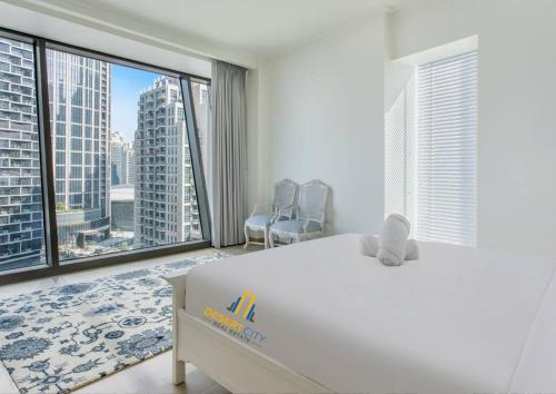 a bedroom with a large white bed and large windows at Luxurious 2 Bed Next to Burj Khalifa, Hosted by Desert City Stays in Dubai