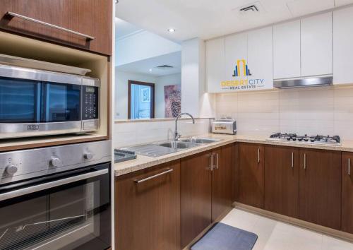 a kitchen with a sink and a microwave at Luxurious 2 Bed Next to Burj Khalifa, Hosted by Desert City Stays in Dubai
