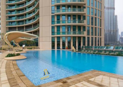 a large swimming pool in front of a tall building at Luxurious 2 Bed Next to Burj Khalifa, Hosted by Desert City Stays in Dubai