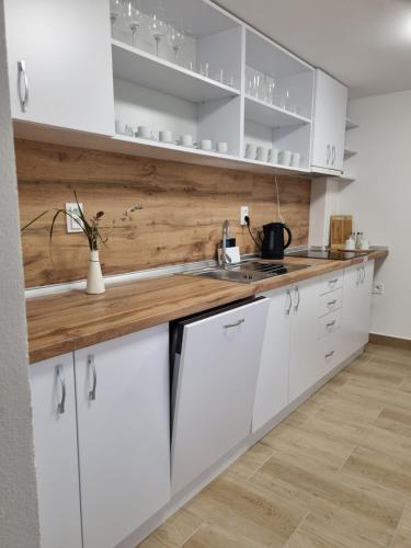 a kitchen with white cabinets and a wooden counter top at Penzión Mateo in Pichne