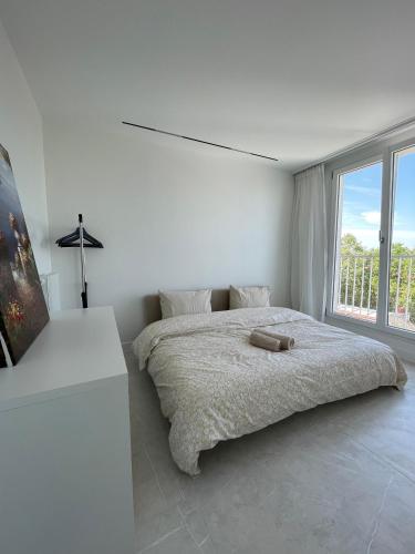 une chambre blanche avec un lit et une grande fenêtre dans l'établissement Elegant Penthouse Paris Panorama, à Colombes