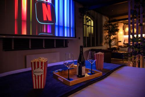 a bottle of wine and two glasses on a table with popcorn at Loft2love, suite de luxe in Saverne