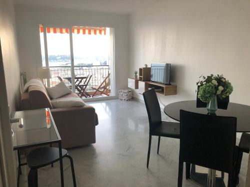 un salon avec un canapé et une table avec des chaises dans l'établissement MENTON APPARTEMENT VUE MER 2 Pièces, à Menton