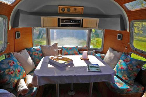 une chambre avec une table et des chaises dans un wagon dans l'établissement Caravane Airstream bord de lac, à Saint-Loubès