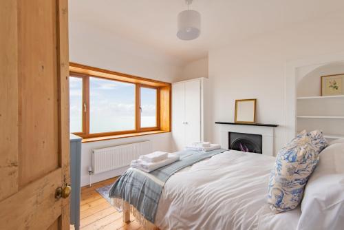 een witte slaapkamer met een bed en een open haard bij Sea Spray Cottage by Bloom Stays in Sandgate
