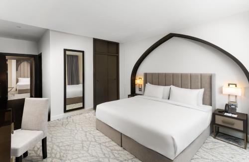 a bedroom with a large white bed and a chair at The Address Serviced Apartments in Al Khobar