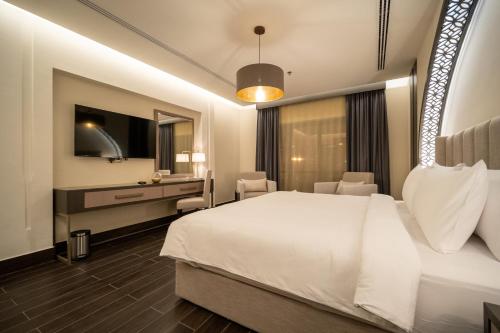 a hotel room with a bed and a desk and a television at The Address Serviced Apartments in Al Khobar