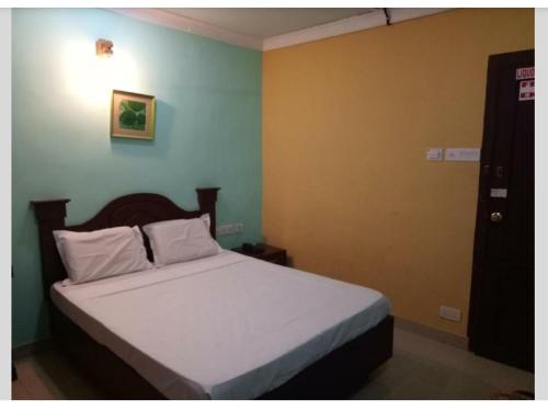 a bedroom with a bed with white sheets at Hotel Priya in Chengannūr