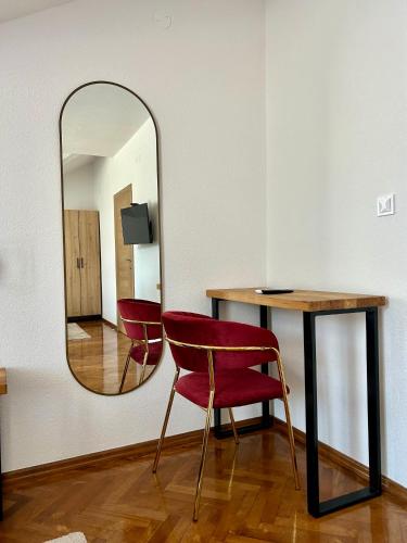a mirror on a wall next to a table and a chair at Motel Marić in Žepče
