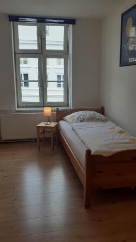 a bedroom with a bed and a table with a lamp at 2-Zimmer-Ferienwohnung-im-1-Obergeschoss in Lübeck