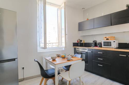 une cuisine avec une table et des chaises et un micro-ondes dans l'établissement Cosy et Calme proche métro Montplaisir, à Lyon