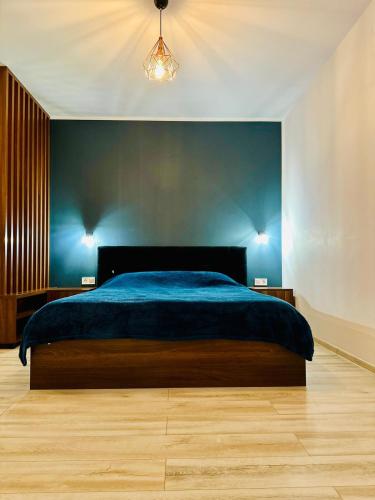 a bedroom with a bed and a blue wall at BB Apartaments Dream Village in Iaşi