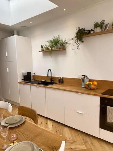 une cuisine avec des placards blancs et une table en bois avec une table dans l'établissement Maison 5min du vieux-Lille avec extérieur pour 1 à 6 personnes, à La Madeleine